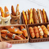 A set of miniature dollhouse baguette baskets filled with small bread loaves and a UFA logo.
