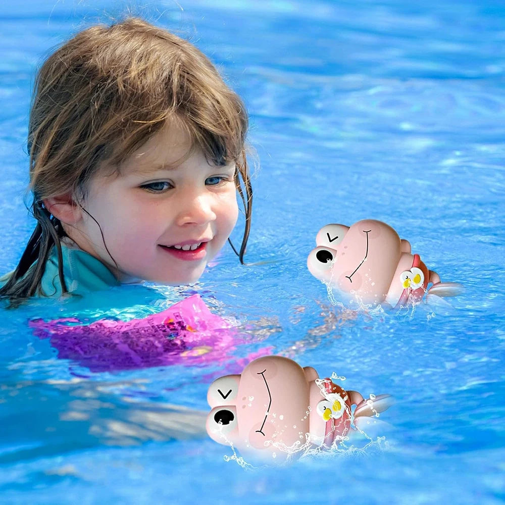 A young girl is smiling while playing in blue water with several pink and white swimming frog toys.