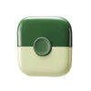 A green and cream dual-edge baby hair cutting comb with a round opening.