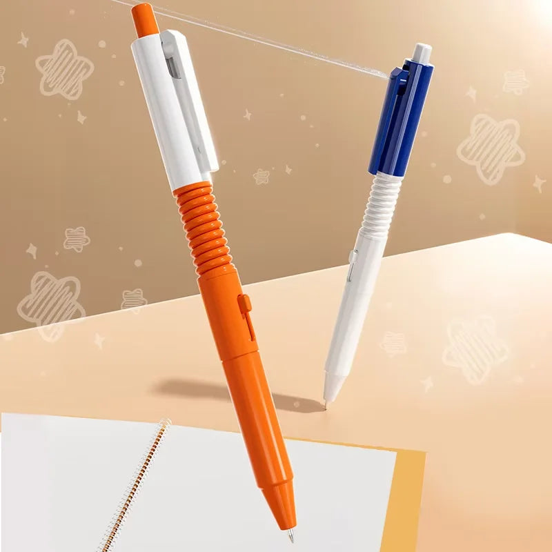 An orange and white squirt water spray ballpoint pen is shown next to a blue and white pen on a light background.