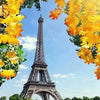 A vibrant view of the Eiffel Tower framed by bright yellow autumn leaves against a blue sky.