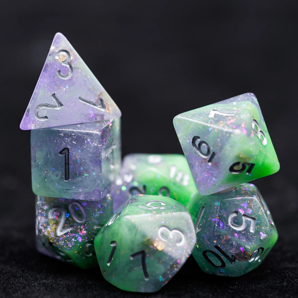 A stack of translucent green and purple glitter resin polyhedral dice set for tabletop role-playing games