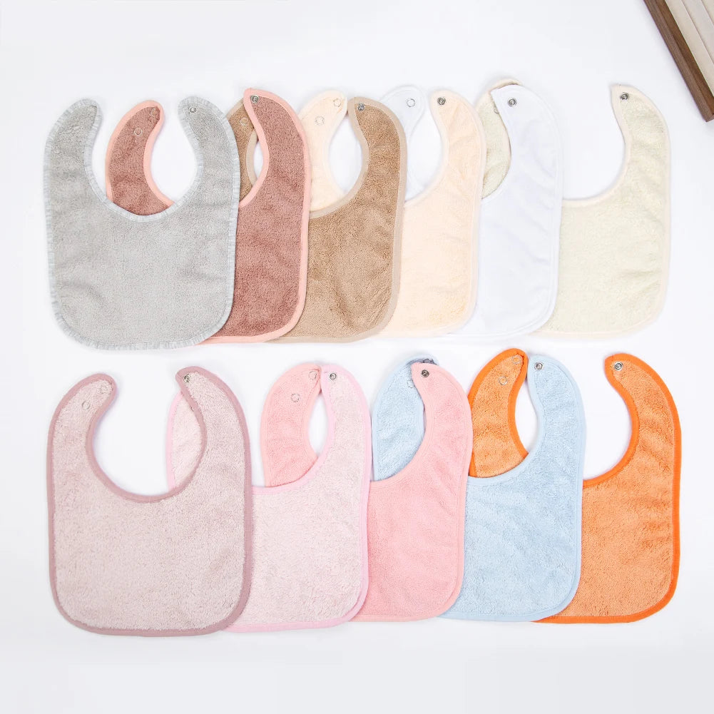 A collection of soft cotton baby bibs in various pastel and neutral colors arranged horizontally.
