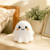 A white, glowing ghost-shaped stress ball or fidget toy resting on a light wooden surface.