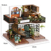 A wooden miniature dollhouse kit featuring furniture, warm lighting, and decorative elements.