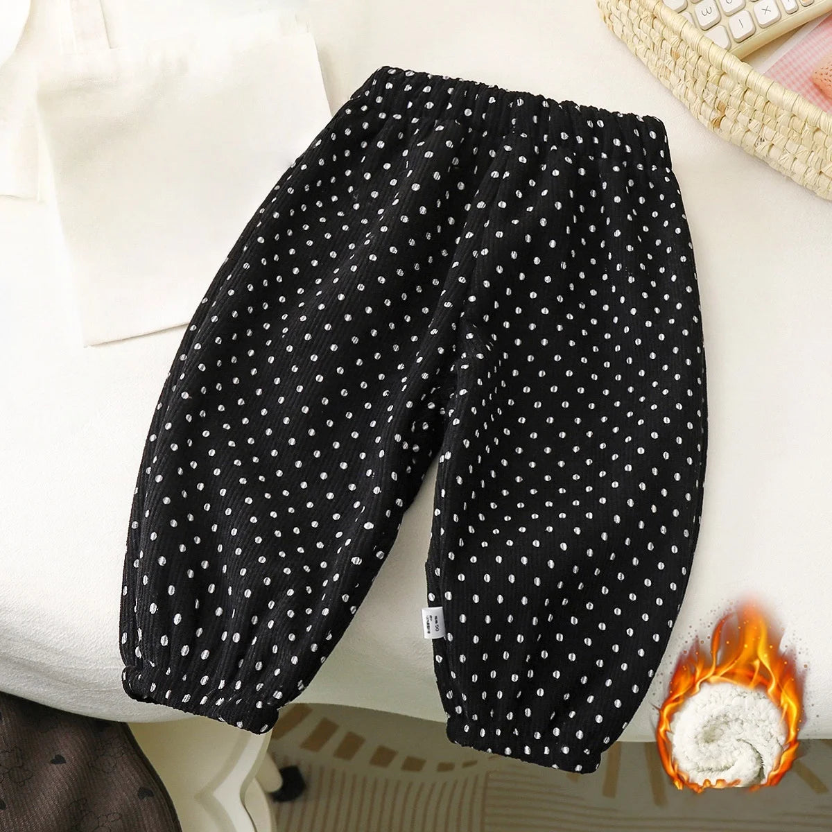Black fleece-lined polka dot pants laid flat on a white surface.