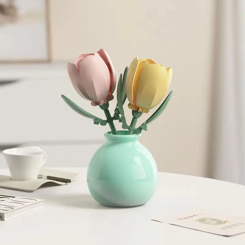A small vase holds two artificial flowers, one pink and one yellow, on a white table.