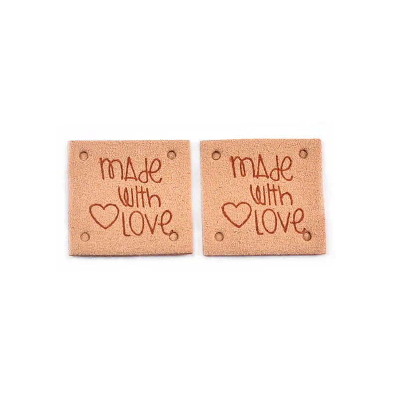 A set of two embossed leather labels with the text Made with Love stamped on them.