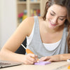 A woman is using a yellow tool to apply foam grip sleeves onto a purple utensil.