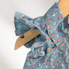 A light blue floral print girls' sleeveless shirt and shorts set displayed on a wooden hanger.