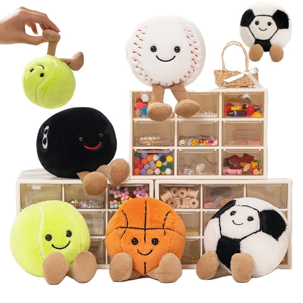 A collection of plush sports balls in various colors including yellow, black, and orange, displayed on a wooden box.