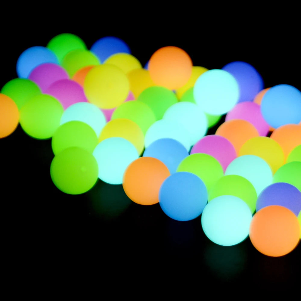 A collection of brightly colored glow-in-the-dark silicone beads scattered across a dark surface.
