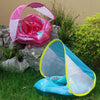 Pink inflatable baby seat ring with a clear sunshade canopy resting on green foliage.