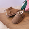 A pair of tan suede winter snow boots and several colorful knitted socks are displayed on a wooden surface.