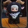 A dark brown, fluffy plush doll with large ears and a white face is displayed on a wooden surface.