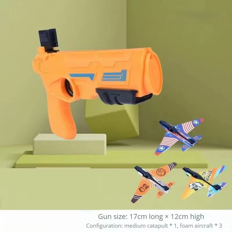 Orange airsoft gun toy and three foam airplanes displayed on a light green surface.
