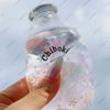 A hand holds a clear bottle filled with liquid and glitter, labeled Chiboki, against a light blue background.