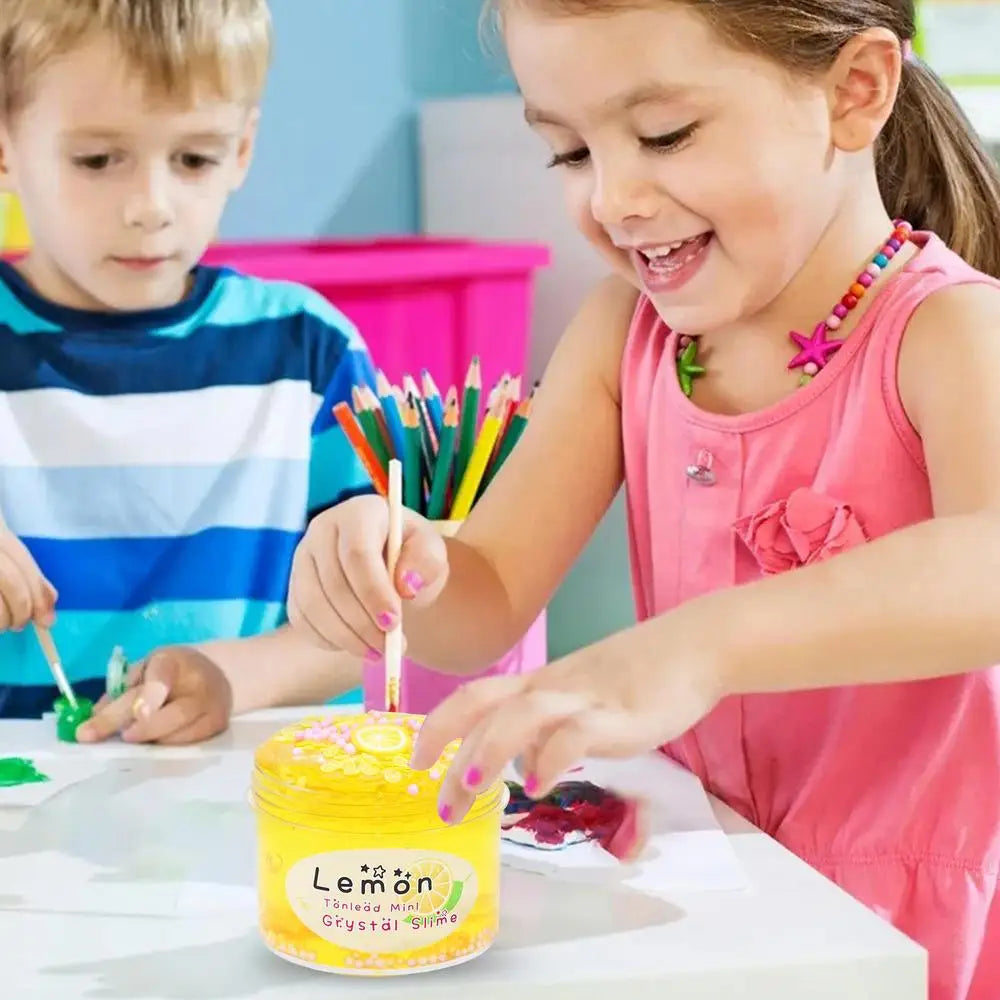 A young girl is making yellow slime putty with colorful sticks and ingredients on a white table.