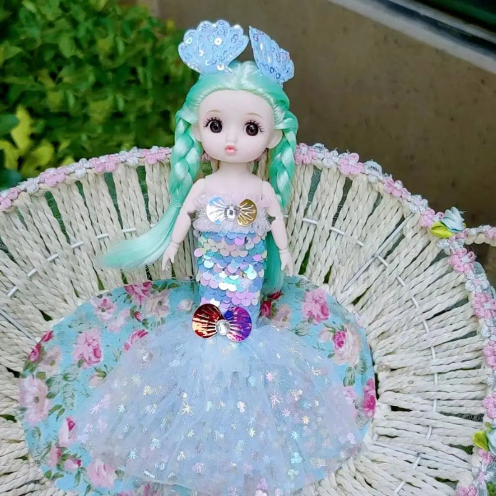 A mermaid doll with teal hair and a sparkly blue dress adorned with sequins and floral accents sits in a woven basket.