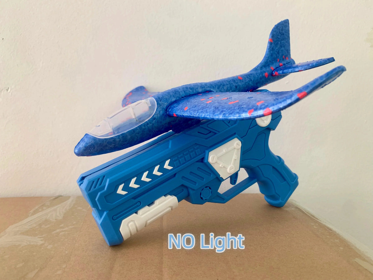 A blue foam glider catapult toy gun with a translucent nose piece resting on brown cardboard.