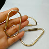 A hand holds a brass keychain with a locking carabiner clip.