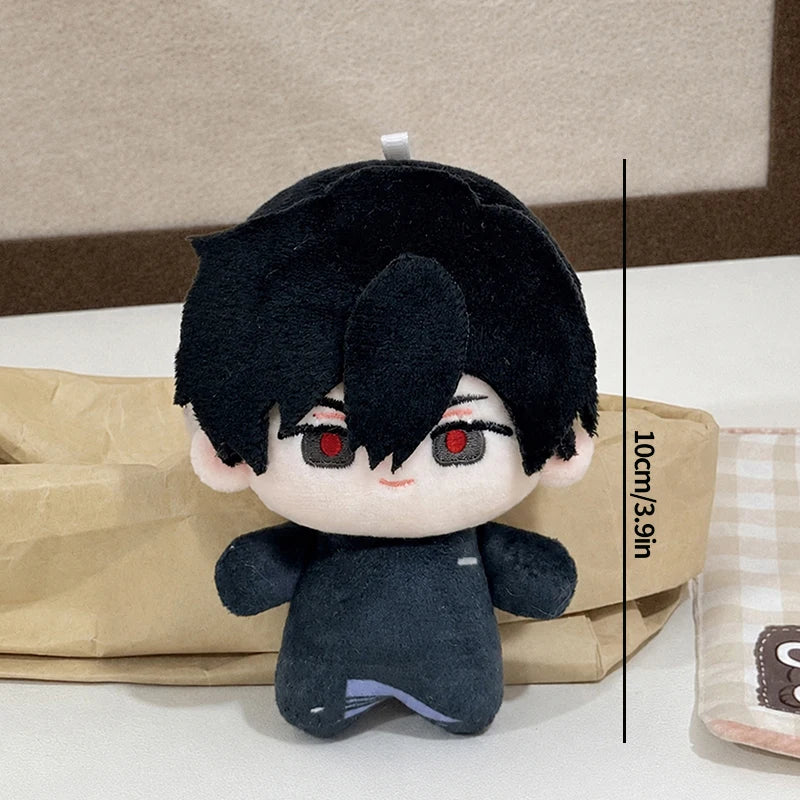 A black plush keychain featuring an anime character with dark hair and red eyes, displayed against a brown paper background.