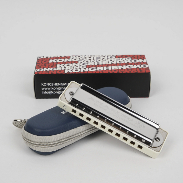 A white and black diatonic harmonica is shown next to its packaging box.