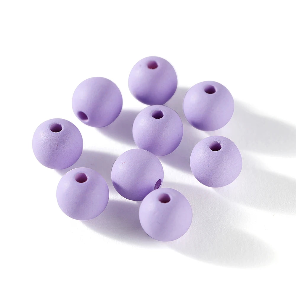 A collection of matte purple acrylic round beads scattered on a white surface.