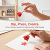 Hands are using a red sponge stamp to create a star print on white paper for arts and crafts.