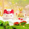 A clear glass figurine of a cute cat with a strawberry mousse tower and an octopus cat pendant charm surrounded by green moss