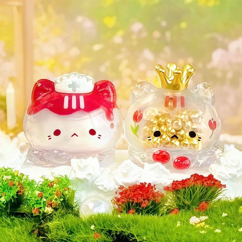 A clear glass figurine of a cute cat with a strawberry mousse tower and an octopus cat pendant charm surrounded by green moss