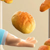 A realistic pretend play food set showing baked bread rolls and a loaf of bread being held by a hand.