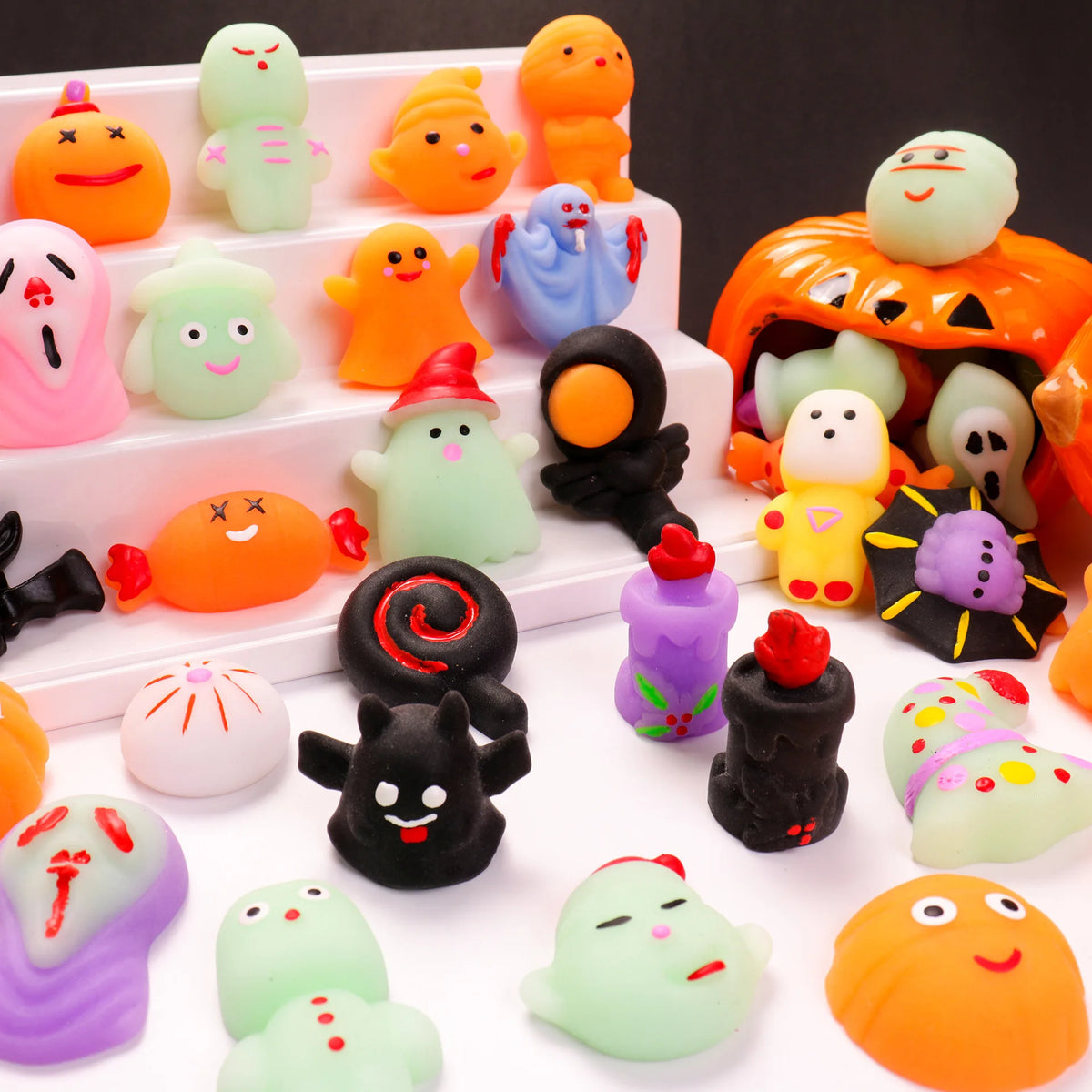 A collection of soft, squishy Halloween-themed toys in various colors like orange, green, and purple.