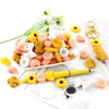 A collection of yellow, pink, and white silicone flower and leaf beads used for jewelry making, displayed on a white plate.