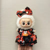 A doll wearing a Halloween pumpkin costume set featuring orange and black fabric with a floral bow