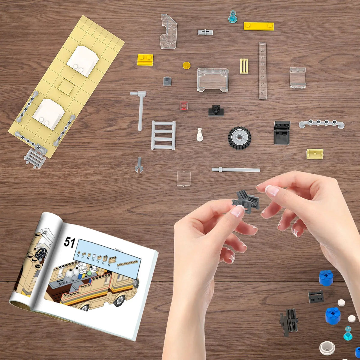 A collection of plastic building blocks and components for an RV model kit laid out on a wooden surface.