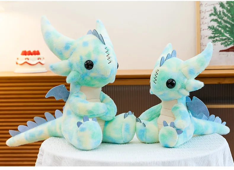 A soft teal and light blue Toothless Dragon plush toy sitting on a white cloth.