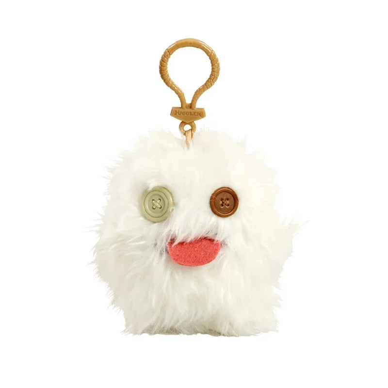 A white fluffy plush monster with large brown eyes and a pink tongue attached to a gold keychain.