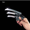 A hand holds a silver retractable mechanical wolf claw prop with flexible knuckles against a black background.