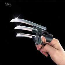 A hand holds a silver retractable mechanical wolf claw prop with flexible knuckles against a black background.