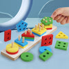 A hand is placing wooden geometric shape sorter puzzles onto a wooden board with various colored shapes.