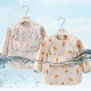 A light pink toddler feeding bib with long sleeves and a floral pattern is displayed against a white background.