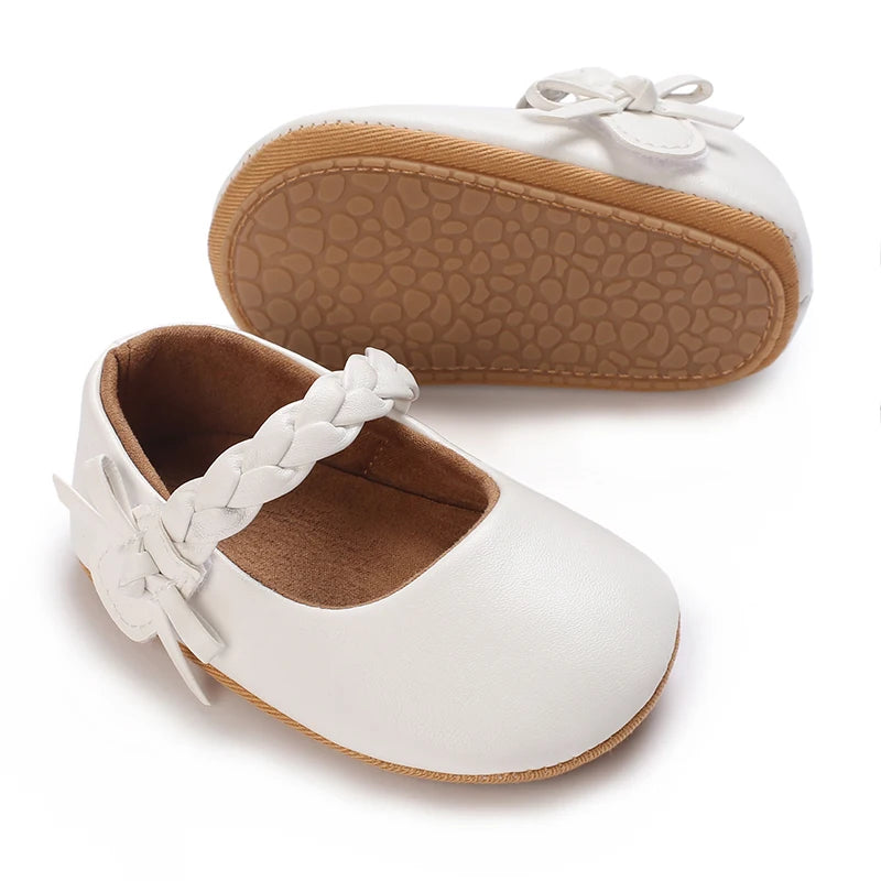 White moccasin shoes for a baby girl featuring white lace trim and a bow on the toe
