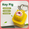 Gelber Schlüssel-Schwein-Fidget-Anhänger mit silberner Schlüsselring und Ladeanschluss sichtbar.
