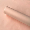 A roll of translucent tissue paper sheets in a pale pink color lying on a light pink surface.