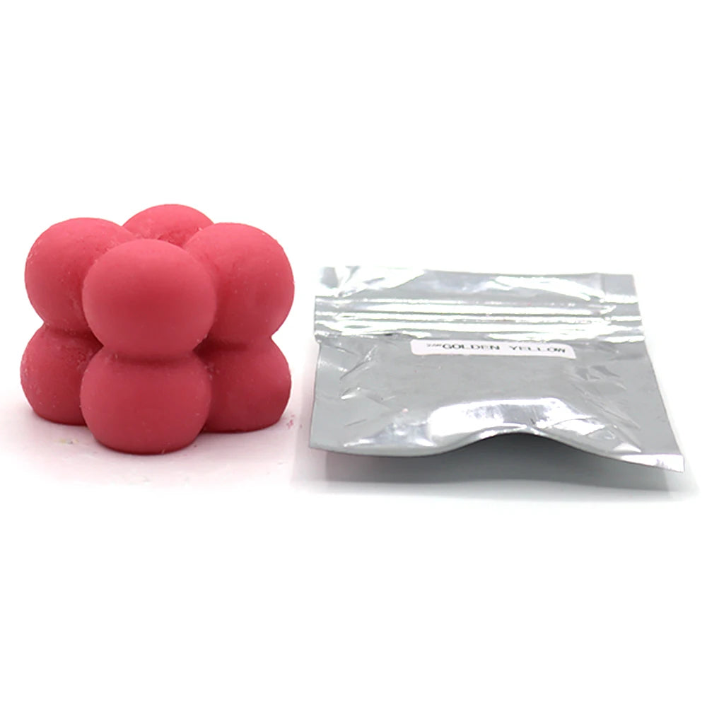 A pile of pink candle dye chips for soy wax, beeswax, and paraffin wax, packaged in a clear plastic bag.