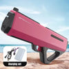 A pink high-pressure electric water gun is shown with its charging set on a sandy surface.