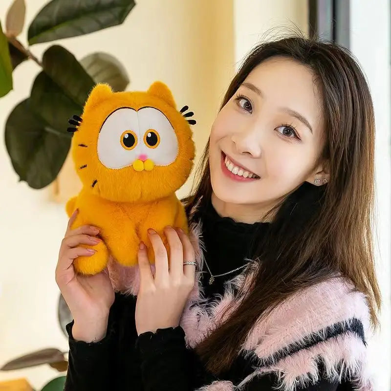 A woman is holding an orange Garfield plush doll with large eyes and black whiskers.