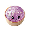 A round, translucent purple glitter sensory squishy fidget toy with cute facial features.