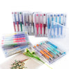 A collection of DIY beaded ballpoint pen kits in clear plastic containers and a wooden surface.